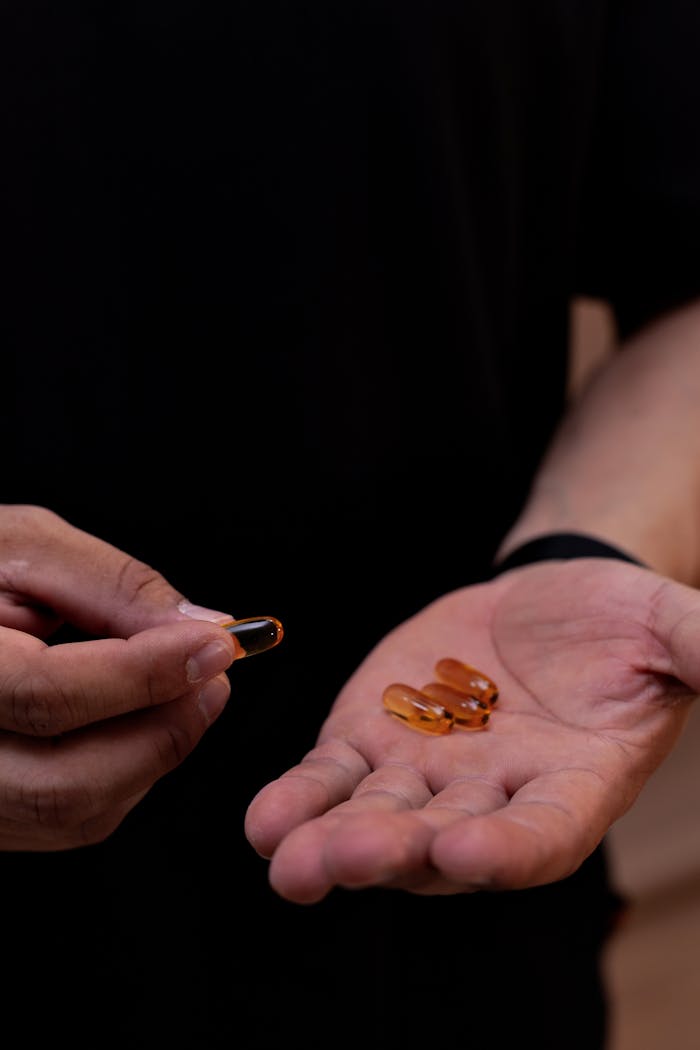 A close-up view of a hand holding orange vitamin capsules, emphasizing health and nutrition.