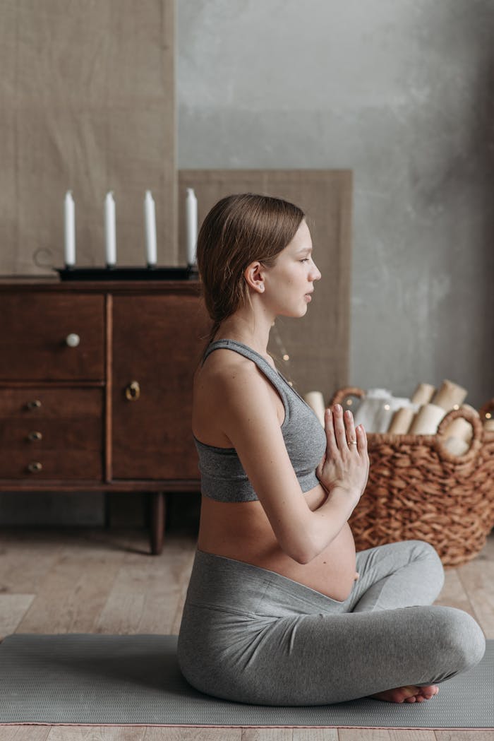 Pregnant woman meditating in a cozy home setting, emphasizing health and relaxation.