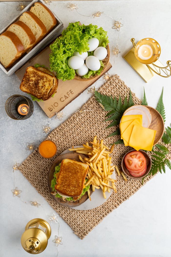 Elegant flat lay of sandwich, fries, cheese, and bread in modern setup.